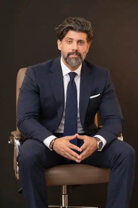 Mudassar Khan, seated portrait in a navy suit